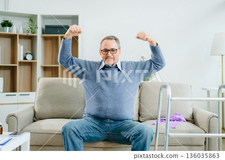 A senior man flexes his arms in celebration of rehabilitation success at home, showcasing strength, independence, wellness A senior man flexes his arms in celebration of rehabilitation success at home, showcasing strength, independence, wellness 136035863