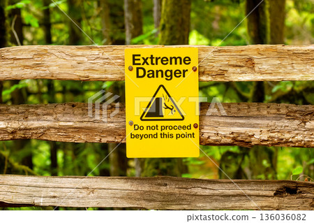 Sign "Extreme danger" in the trail along the canyon in the forest. 136036082