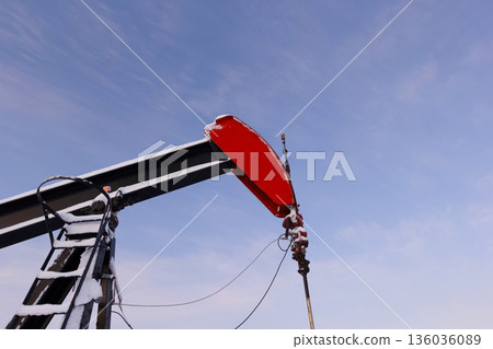 Oil Pumpjack's horsehead against blue and pink sky. Oil Pumpjack's horsehead against blue and pink sky. 136036089