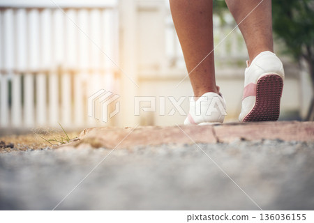Sport sneakers footwear young woman knelt down do up shoelaces. Ready running shoes in sport exercise jogging person. Close up hands tie up runner shoelaces in fitness gym healthy person lifestyle. 136036155