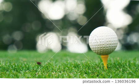Golf ball on tee in green golf field with recreation sport training course. Tee and ball Sports Equipment in Golf Tournament. 136036196
