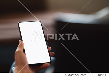 Young woman sitting in chair with modern smartphone with white screen Young woman sitting in chair with modern smartphone with white screen 136038551
