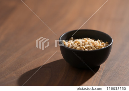 Pine nuts in a black bowl on wood table closeup Pine nuts in a black bowl on wood table closeup 136038560