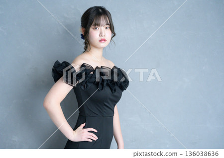 Woman in a black dress against a gray background 136038636