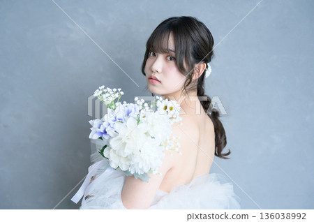 Woman wearing a wedding dress against a gray background Woman wearing a wedding dress against a gray background 136038992