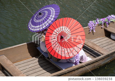 A woman in a kimono on a boat holding a Japanese umbrella 136039238