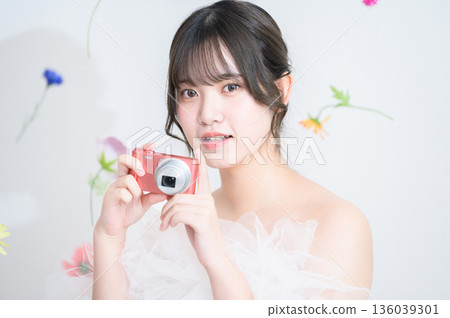 A woman wearing a wedding dress and holding a camera A woman wearing a wedding dress and holding a camera 136039301