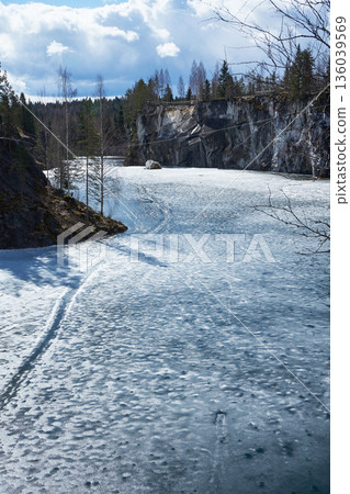 Frozen lake with ice and snow in Ruskeala mountain park. Winter nature scene with quarry cliff and forest landscape Frozen lake with ice and snow in Ruskeala mountain park. Winter nature scene with quarry cliff and forest landscape 136039569