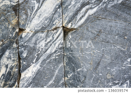 Uneven texture of real marble, background. Blue grey rock surface with cracks and white veins for interior design. Natural stone material. 136039574