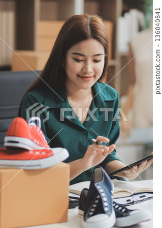 Starting small businesses SME owners female entrepreneurs check online orders to prepare to pack the boxes, sell to customers, sme business ideas online. Starting small businesses SME owners female entrepreneurs check online orders to prepare to pack the boxes, sell to customers, sme business ideas online. 136040841