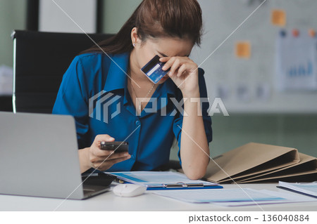 Young businesswoman is holding two credit cards with a worried expression, trying to decide which one to use to pay off her debt Young businesswoman is holding two credit cards with a worried expression, trying to decide which one to use to pay off her debt 136040884