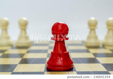 Standing red pawn positioned forward with two blurred white pawns representing frontline leadership Standing red pawn positioned forward with two blurred white pawns representing frontline leadership 136041354