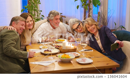 Friends taking group selfie at cheerful dinner party 136041604