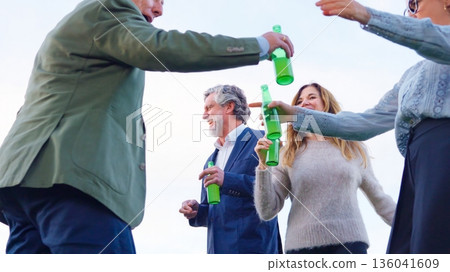 Friends toasting with beer bottles outdoors celebrating success 136041609