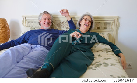 Senior couple laughing together in bed enjoying morning Senior couple laughing together in bed enjoying morning 136041617