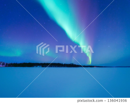 Panoramic horizontal view of the aurora borealis dancing over a frozen lake in Scandinavia.  136041936