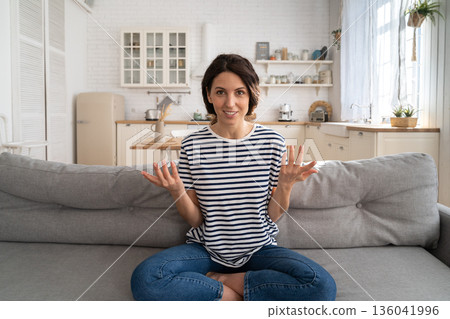 Smiling woman vlogger influencer recording new content to vlog, looking at webcam, sitting on couch. Smiling woman vlogger influencer recording new content to vlog, looking at webcam, sitting on couch. 136041996