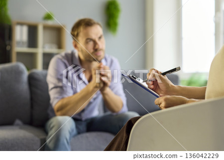 Closeup view of therapist taking notes as patient speaks during counseling Closeup view of therapist taking notes as patient speaks during counseling 136042229