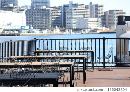露台上擺放著桌椅，可以隱約看到大海、城市建築群和天空。 136042894
