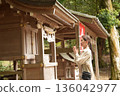 Senior woman praying at a shrine 136042977
