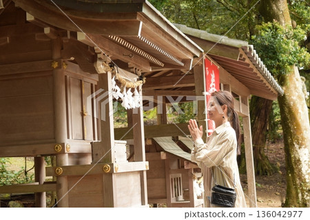 Senior woman praying at a shrine 136042977