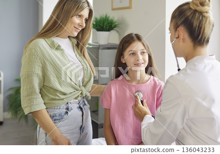 Mother and pediatrician with stethoscope during child checkup in clinic room Mother and pediatrician with stethoscope during child checkup in clinic room 136043233