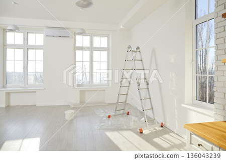 Step ladder and paint bucket standing in empty room in new house with freshly painted white walls. Step ladder and paint bucket standing in empty room in new house with freshly painted white walls. 136043239