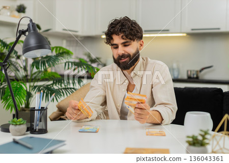 Indian man counting euro cash savings in neat stacks planning budget dreaming about future purchase Indian man counting euro cash savings in neat stacks planning budget dreaming about future purchase 136043361