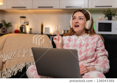 Adult woman with laptop and headphones gets creative idea during remote work session smiles inspired 136043368