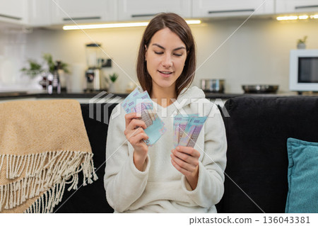 Young woman counts hryvnia money cash plans invest bonus and salary dreams of purchase future goal Young woman counts hryvnia money cash plans invest bonus and salary dreams of purchase future goal 136043381