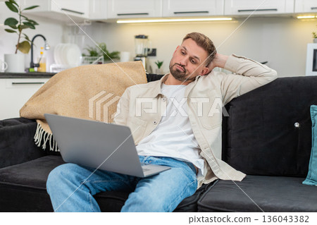 Young man works on laptop tired and demotivated deep sigh low energy struggles to focus long session Young man works on laptop tired and demotivated deep sigh low energy struggles to focus long session 136043382