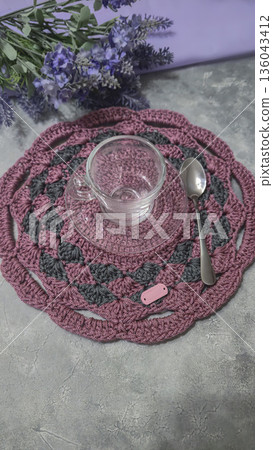 Knitted round lilac placemats on a gray background. Interior decor. Green plates. 136043412