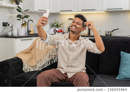 Indian man holds house key keychain smiles takes smartphone selfie keys posts on social media proud Indian man holds house key keychain smiles takes smartphone selfie keys posts on social media proud 136043464