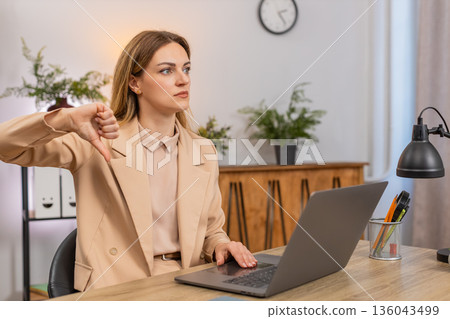Businesswoman shows thumbs down at laptop dislike gesture unhappy face reacts to bad result review 136043499