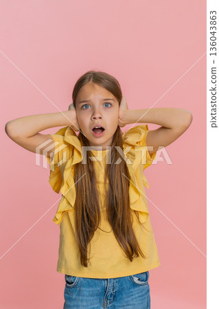 Child girl kid covers ears with hands opens eyes wide showing fear or panic from loud noise or sound Child girl kid covers ears with hands opens eyes wide showing fear or panic from loud noise or sound 136043863