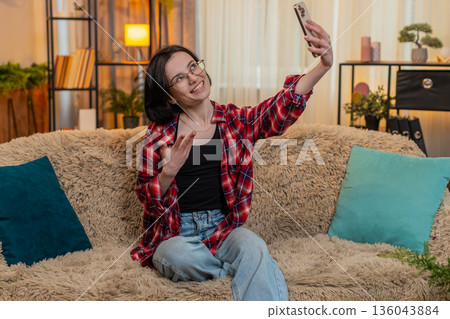 Blogger woman filming vlog stream on smartphone camera at home smiling and interacting with audience 136043884