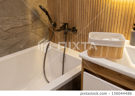 A serene bathing space features a sleek tub, soothing textures, and warm wooden accents inviting moments of tranquility and relaxation A serene bathing space features a sleek tub, soothing textures, and warm wooden accents inviting moments of tranquility and relaxation 136044486