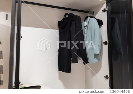 Black and light blue clothes hang neatly in a minimalist closet, inviting creativity and inspiration for stylish ensembles 136044496