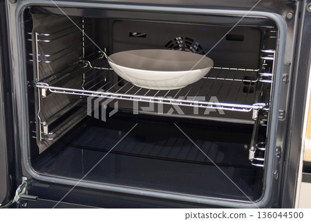 A sleek oven houses a bowl, hinting at a warm meal soon to emerge, filling the kitchen with delightful aromas and comfort 136044500