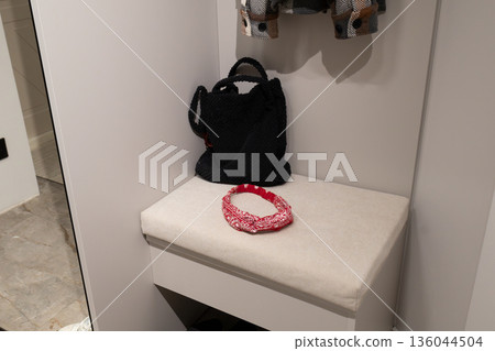 Stylish bag and vibrant headband rest on a comfy bench in a well-lit changing room, inviting fashion enthusiasts to explore more 136044504