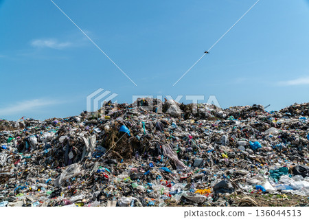 A vast expanse of garbage dominates the landscape, showcasing heaps of trash and plastic under an open sky, highlighting environmental neglect A vast expanse of garbage dominates the landscape, showcasing heaps of trash and plastic under an open sky, highlighting environmental neglect 136044513