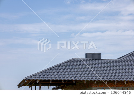 A robust gray roof stands tall under a vast blue sky with soft clouds, showcasing a tranquil scene of architecture and nature A robust gray roof stands tall under a vast blue sky with soft clouds, showcasing a tranquil scene of architecture and nature 136044546