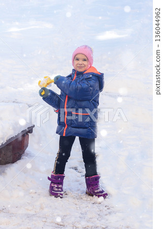 Young girl in blue winter coat and pink hat enjoying snowy day outdoors and playing Young girl in blue winter coat and pink hat enjoying snowy day outdoors and playing 136044962