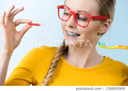 Woman smiling cleaning teeth with braces Woman smiling cleaning teeth with braces 136045069