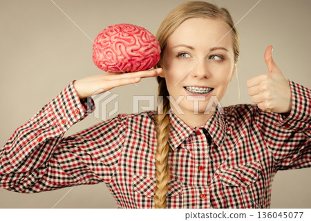 Woman thinking and holding fake brain 136045077