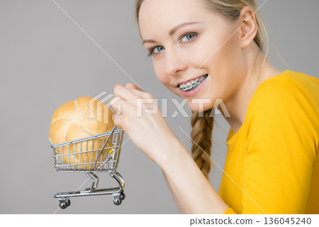 Woman holding shopping cart with bread Woman holding shopping cart with bread 136045240