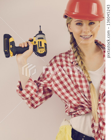 Woman wearing helmet using drill 136045243