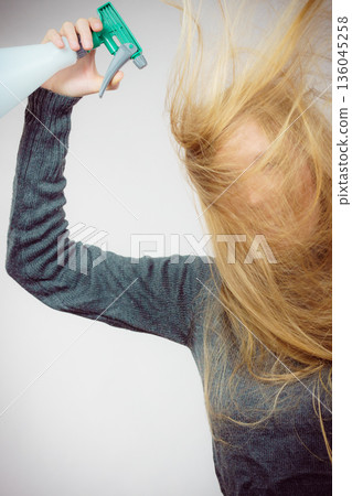 Female messy long hair holds spray bottle Female messy long hair holds spray bottle 136045258