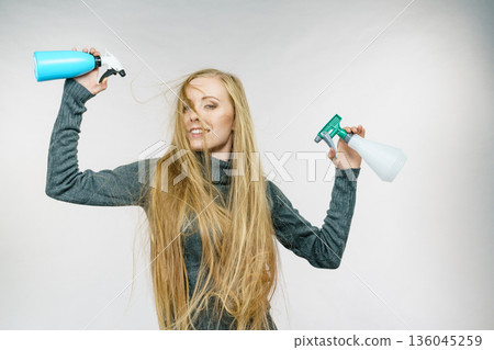 Female messy long hair holds spray bottle 136045259