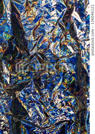 Close-up of iridescent foil texture with crumpled metallic reflections and bold colors Close-up of iridescent foil texture with crumpled metallic reflections and bold colors 136046121